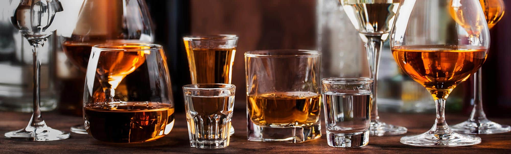 Wood table top with several different kinds of alcoholic drinks on it 