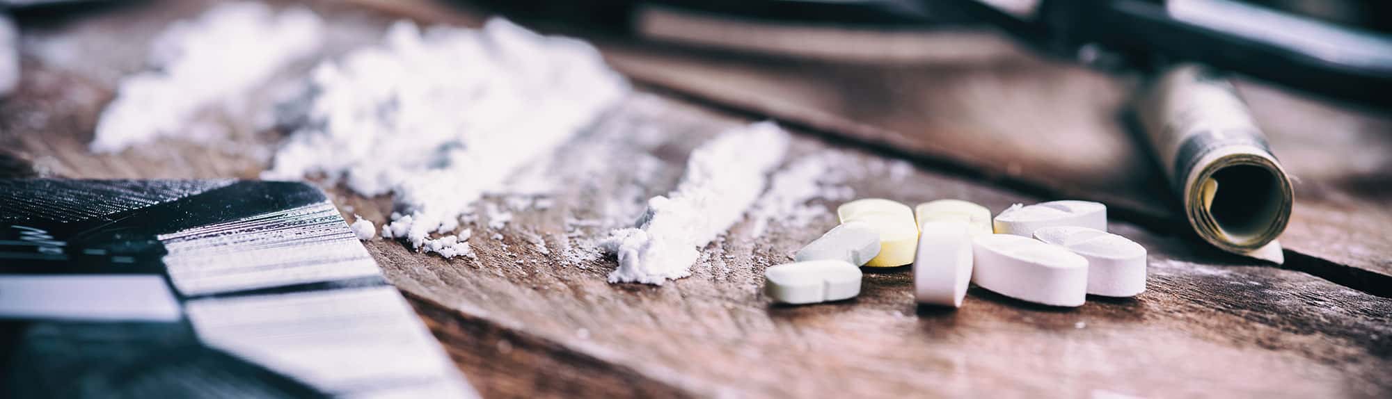 Rolled up dollar bill with powder in short lines and pills