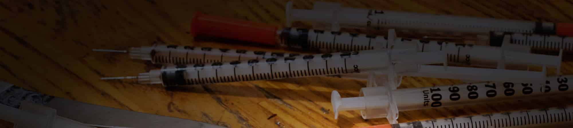 A pile of syringes on wood surface