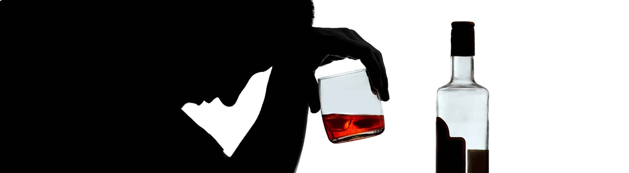 black side profile of person with head on hand and glass of whiskey in hand and bottle of liquor nearby