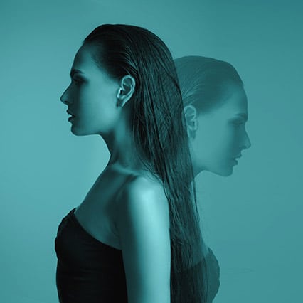 girl with slicked back long hair, faced to one side, a faint outline of her faced in the other direction with a blue hue 