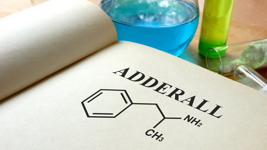 A book is open to a page depicting Adderall and its chemical structures representing the Adderall shortage and how it’s affecting mental health disorders. 