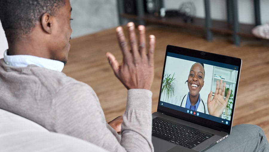 Man speaking with a medical professional through a telehealth online video appointment about treatment for substance use disorder. 