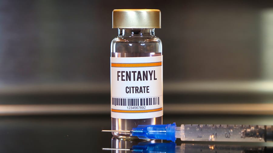 A glass fentanyl bottle next to a syringe represents Biden's State of the Union and fentanyl reform proposal.