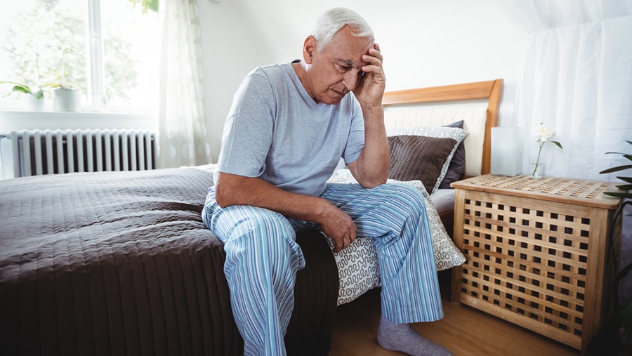 A distressed elderly man sitting on a bed represents substance addiction in senior adults.