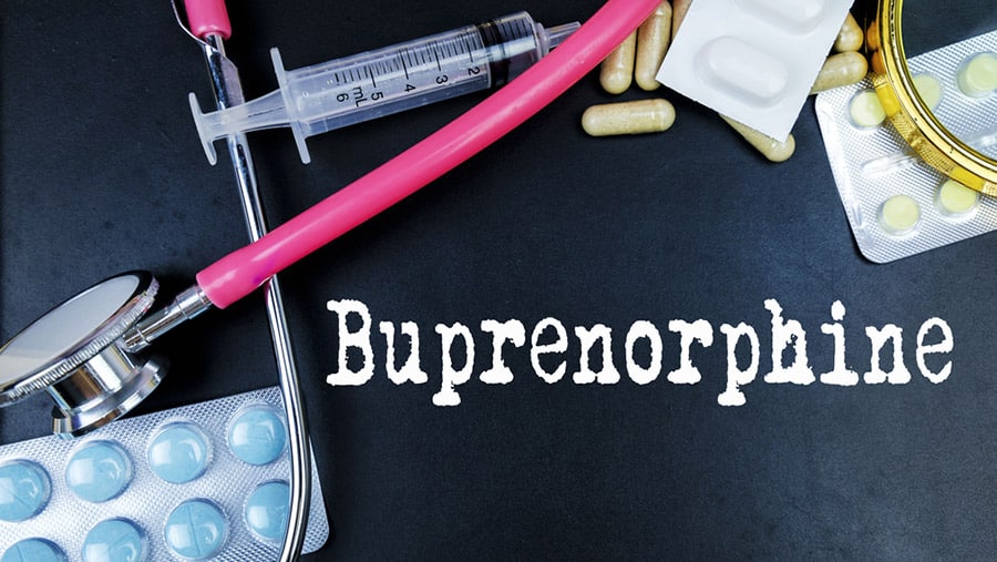On a black background the word buprenorphine is written out next to pills, a syringe and pink stethoscope representing anti-craving medication for drug addiction.
