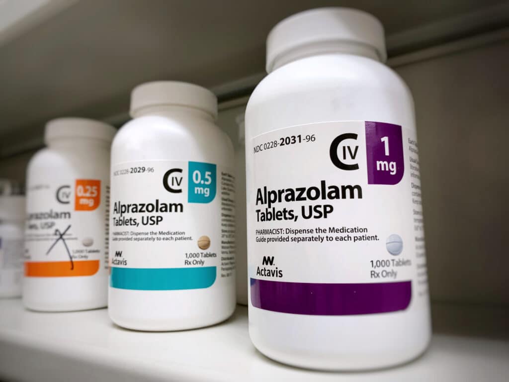 A pharmacy shelf with three different bottles of Alprazolam represents the potential to be addicted to Xanax.