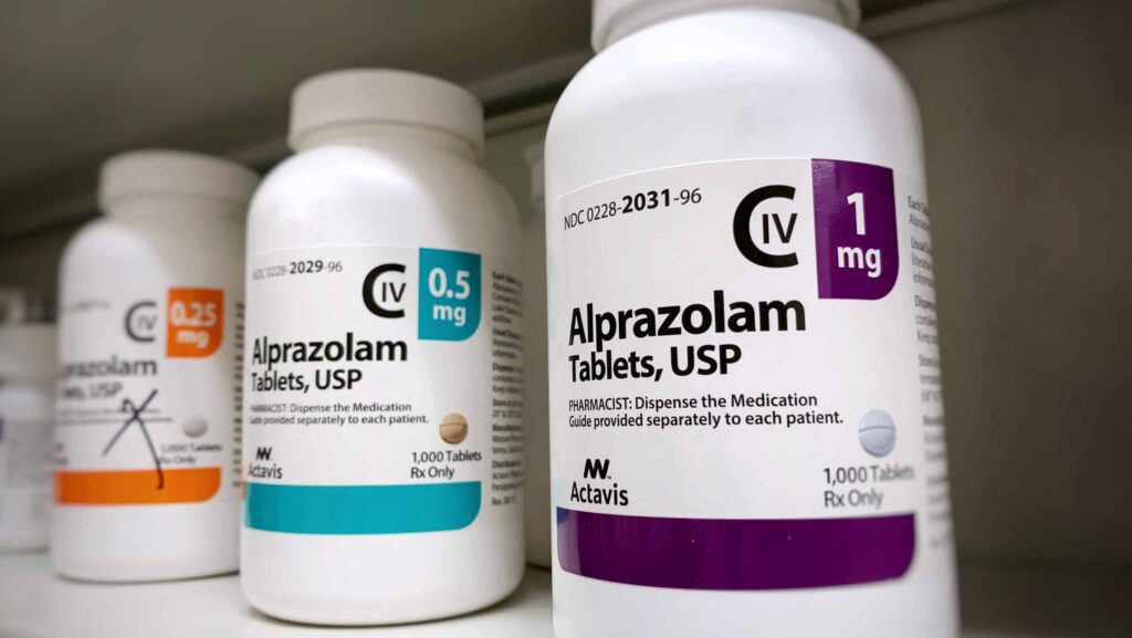 A pharmacy shelf with three different bottles of Alprazolam represents the potential to be addicted to Xanax.