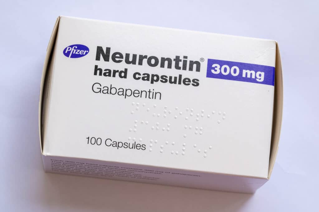 A white and purple box of gabapentin capsules on a white table represents those who question, can I take Xanax with gabapentin?