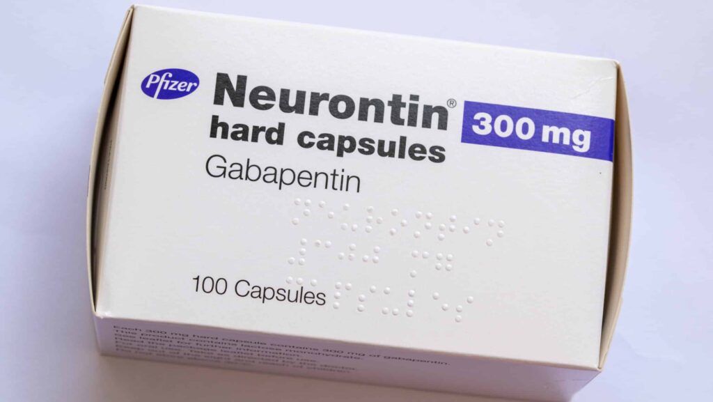 A white and purple box of gabapentin capsules on a white table represents those who question, can I take Xanax with gabapentin?