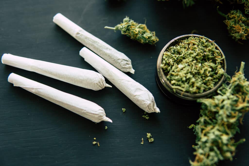 Blunt rolls of cannabis next to ground up cannabis buds represent the need for THC detox in those with a marijuana use disorder.