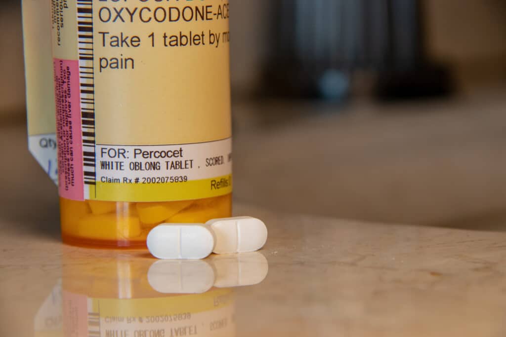 A prescription bottle of Percocet sits on a bathroom counter as the user wonders how long does Percocet stay in urine.