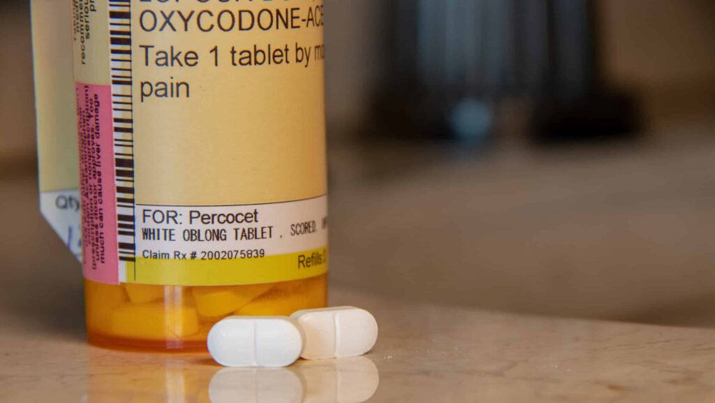 A prescription bottle of Percocet sits on a bathroom counter as the user wonders how long does Percocet stay in urine.