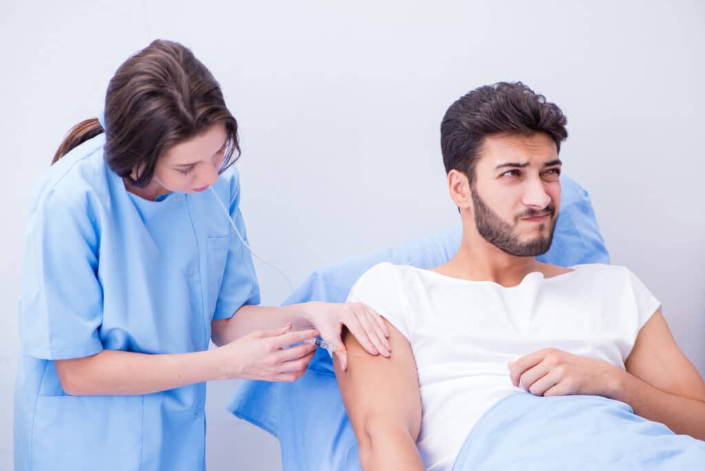 A young man in opioid addiction treatment receiving injection of either Sublocade or Vivitrol by a female clinician.