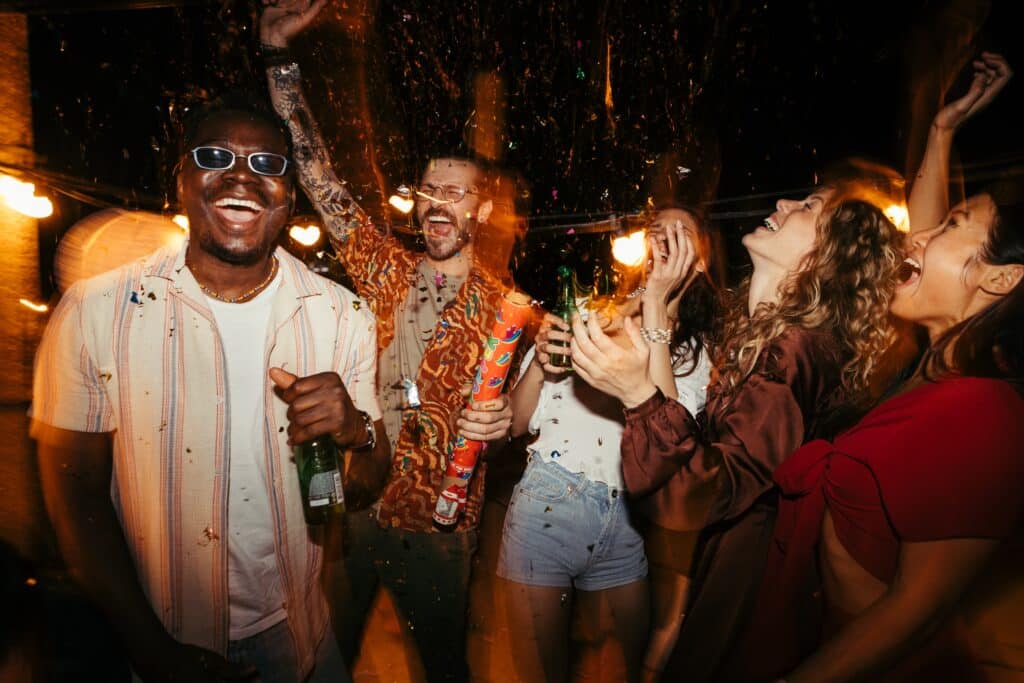 A group of friends in their mid 20s party with drinks in hand. The drinks may contain alcohol or a the substance called lean.
