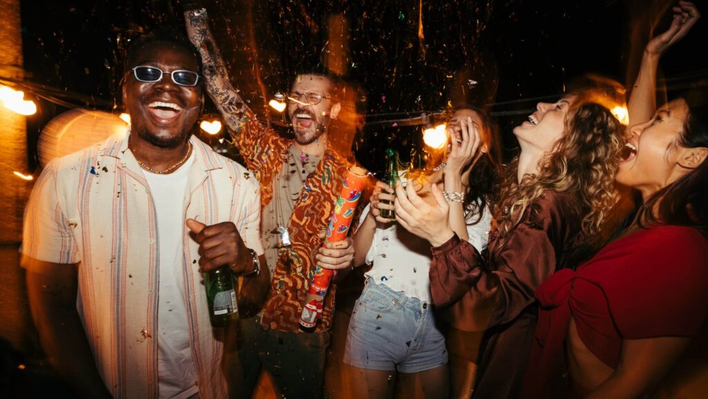 A group of friends in their mid 20s party with drinks in hand. The drinks may contain alcohol or a the substance called lean.