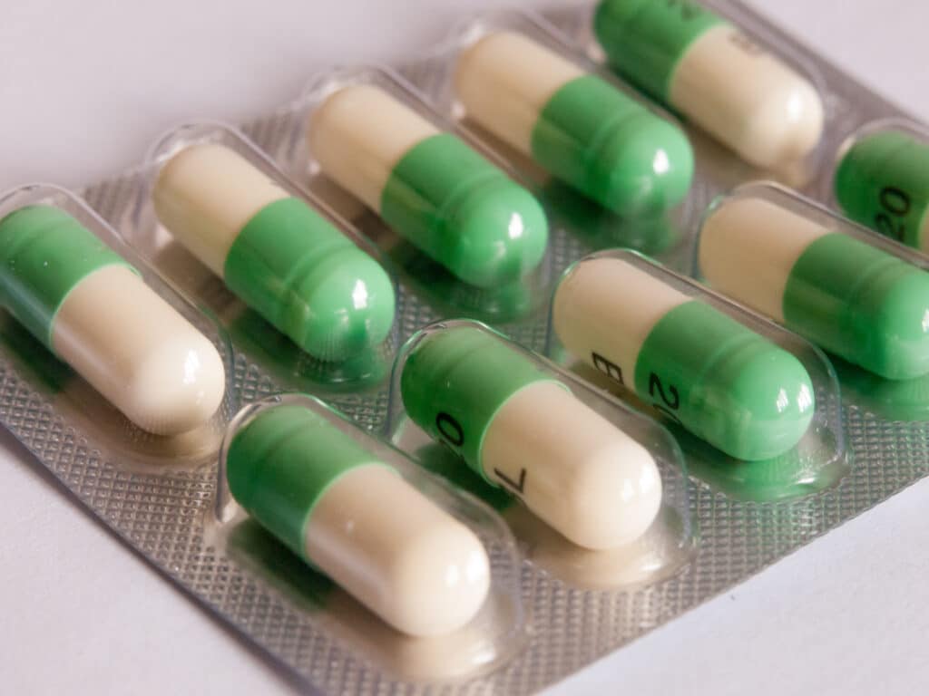 A bubble pack of green and white Prozac capsules lays on a white table represents the risk of a Prozac addiction.