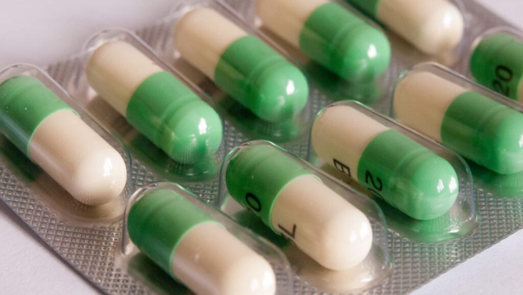 A bubble pack of green and white Prozac capsules lays on a white table represents the risk of a Prozac addiction.