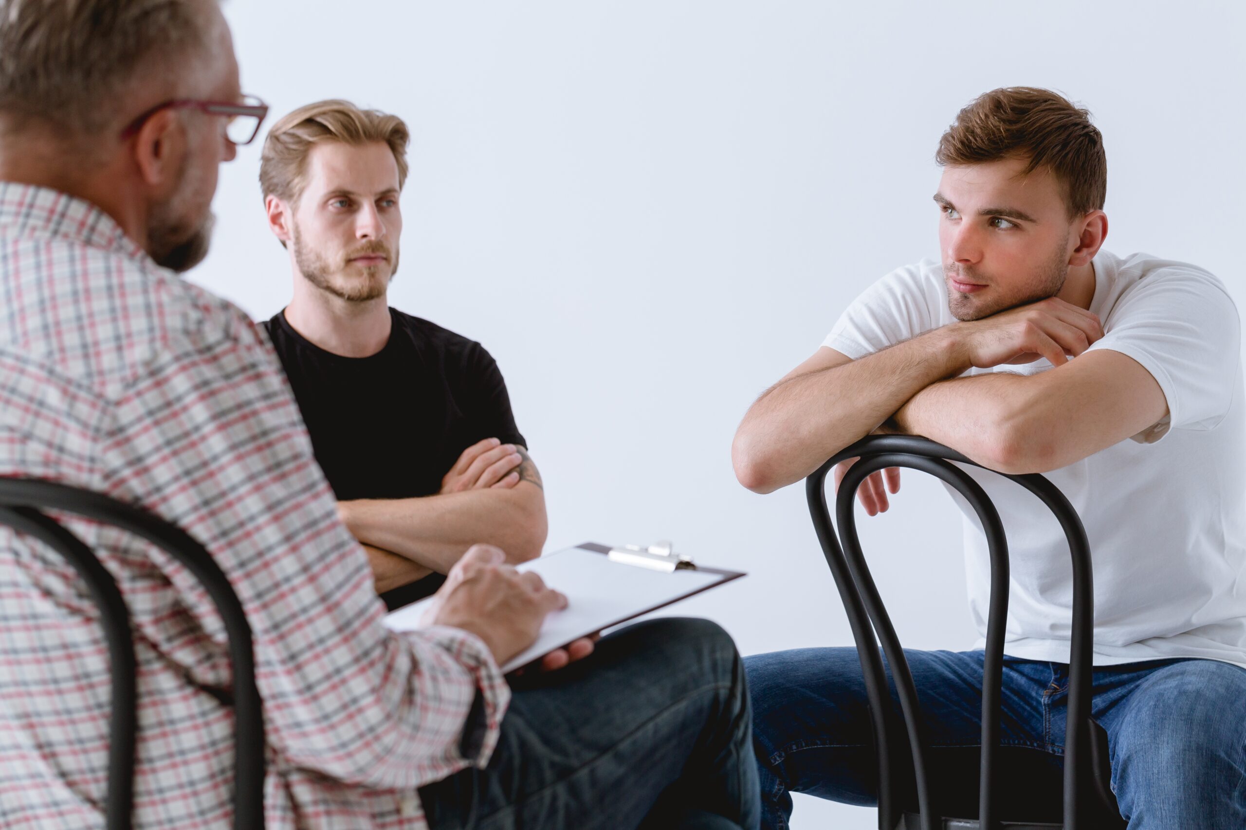 Three men talking to each other sitting in chairs