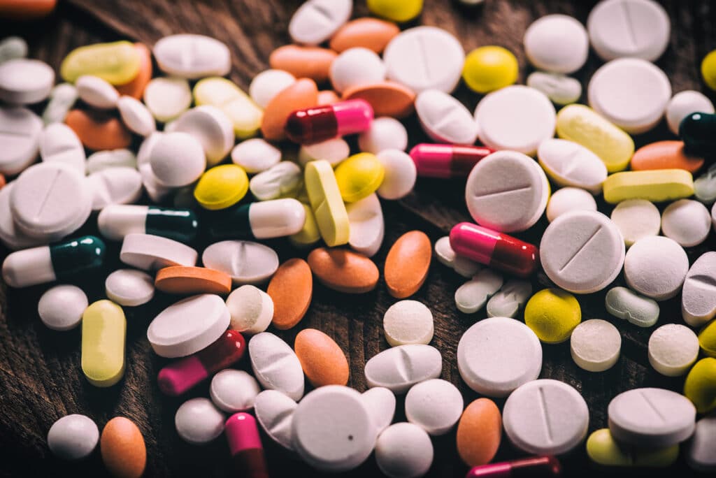 A collection of various pills and tablets laid out on a table represents different types of illicit drugs including gas station heroin.