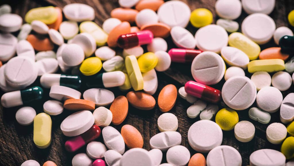 A collection of various pills and tablets laid out on a table represents different types of illicit drugs including gas station heroin.