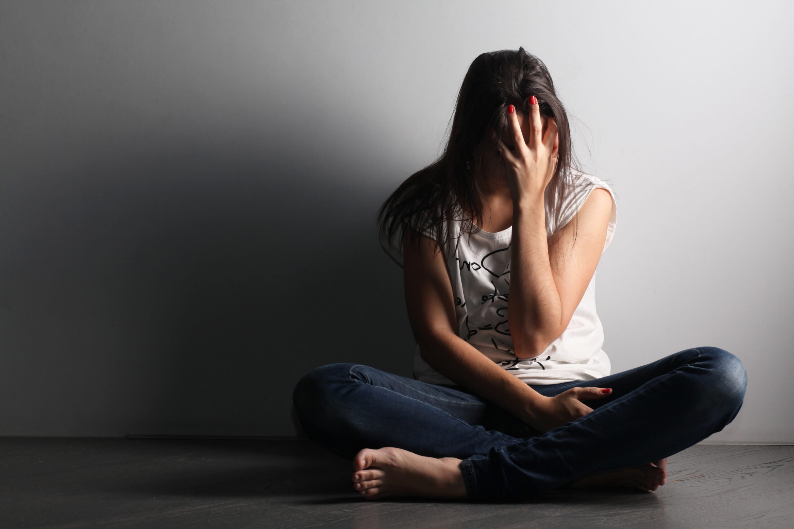 Woman with signs of cocaine addiction sitting on the floor