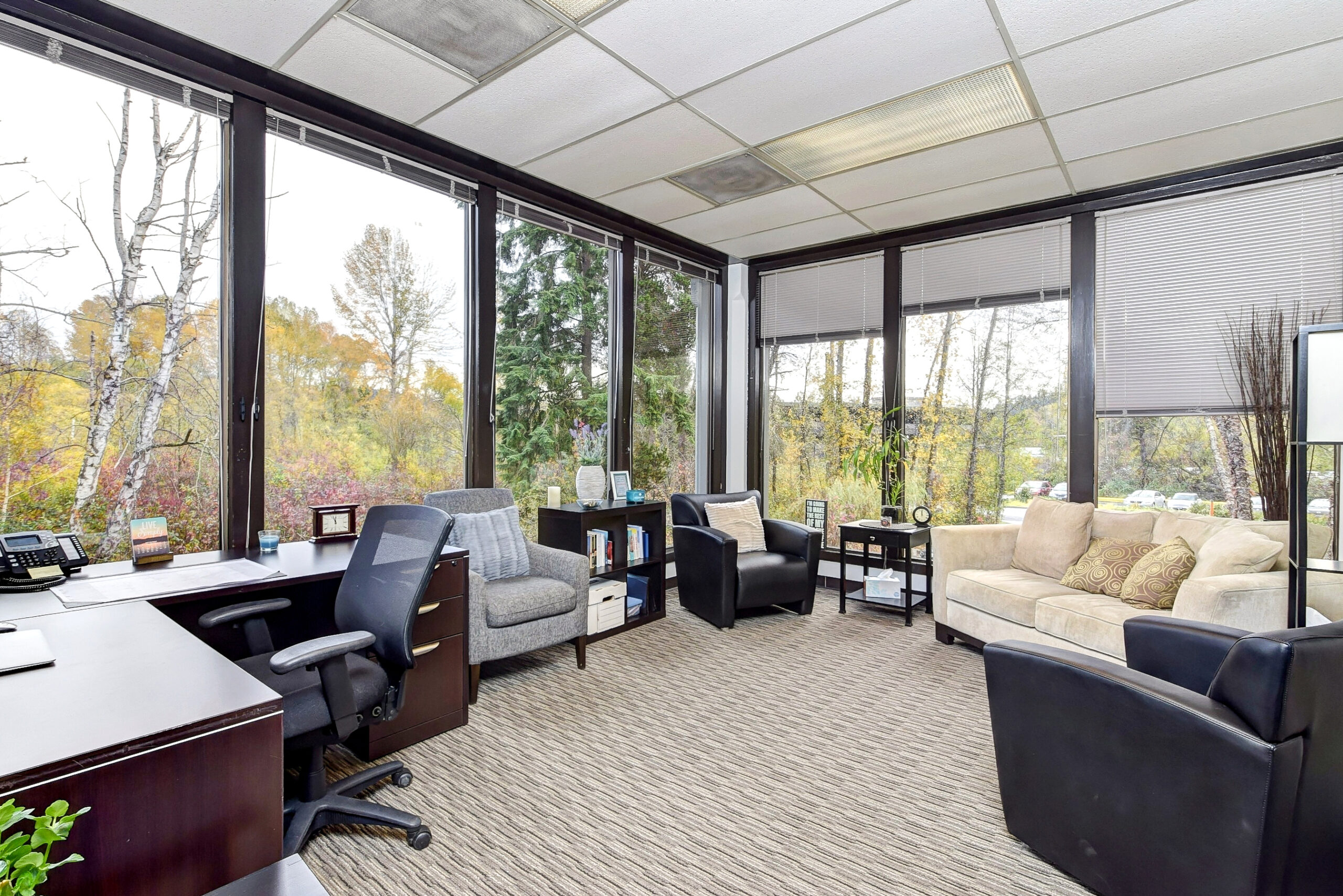 White couch, gray chairs, and brown desk in a therapy setting