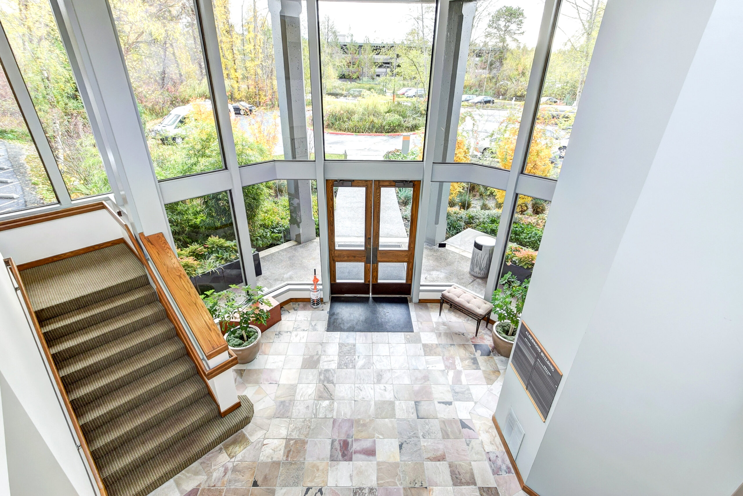 Overhead view of drug rehab entrance with tall glass panes, wooden doors, and brown staircase leading upstairs.