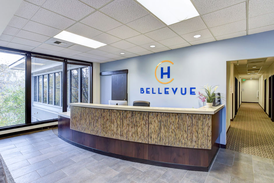 Front desk with Hotel California by the Sea Bellevue sign, brown counter and blue walls