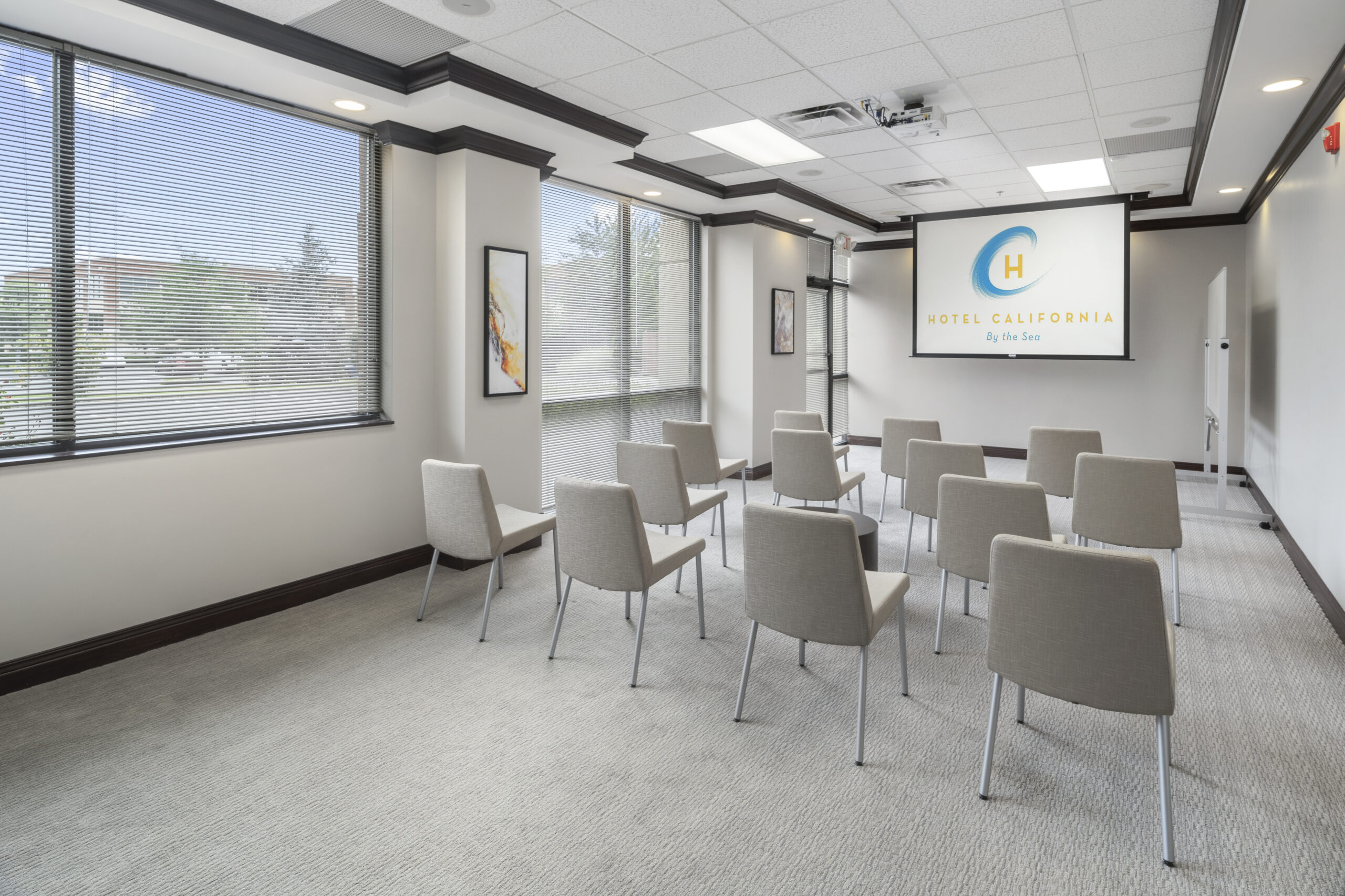 Gray chairs in a row in group therapy for substance abuse room, facing a sign saying Hotel California by the Sea