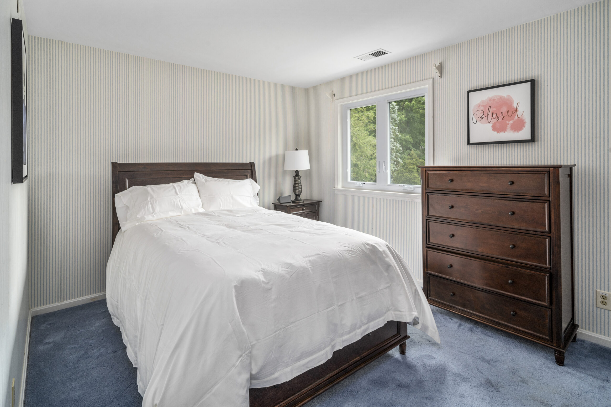 Bed with white bedding and brown dresser in one of our trauma treatment centers in ohio