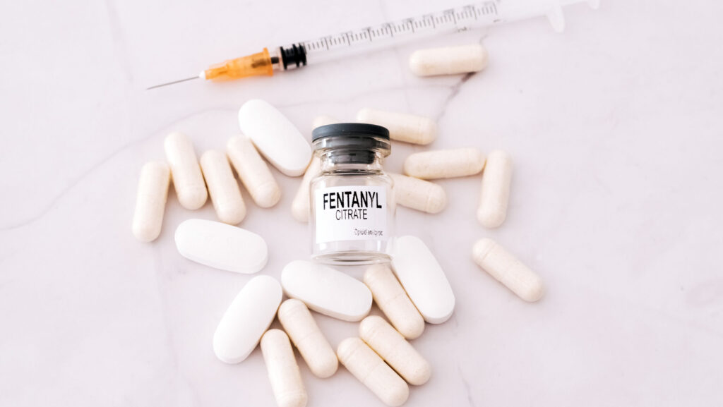 White pills, a syringe and a vile labeled fentanyl citrate lays on a white table. This shows a person may have a fentanyl addiction and may need fentanyl rehab.