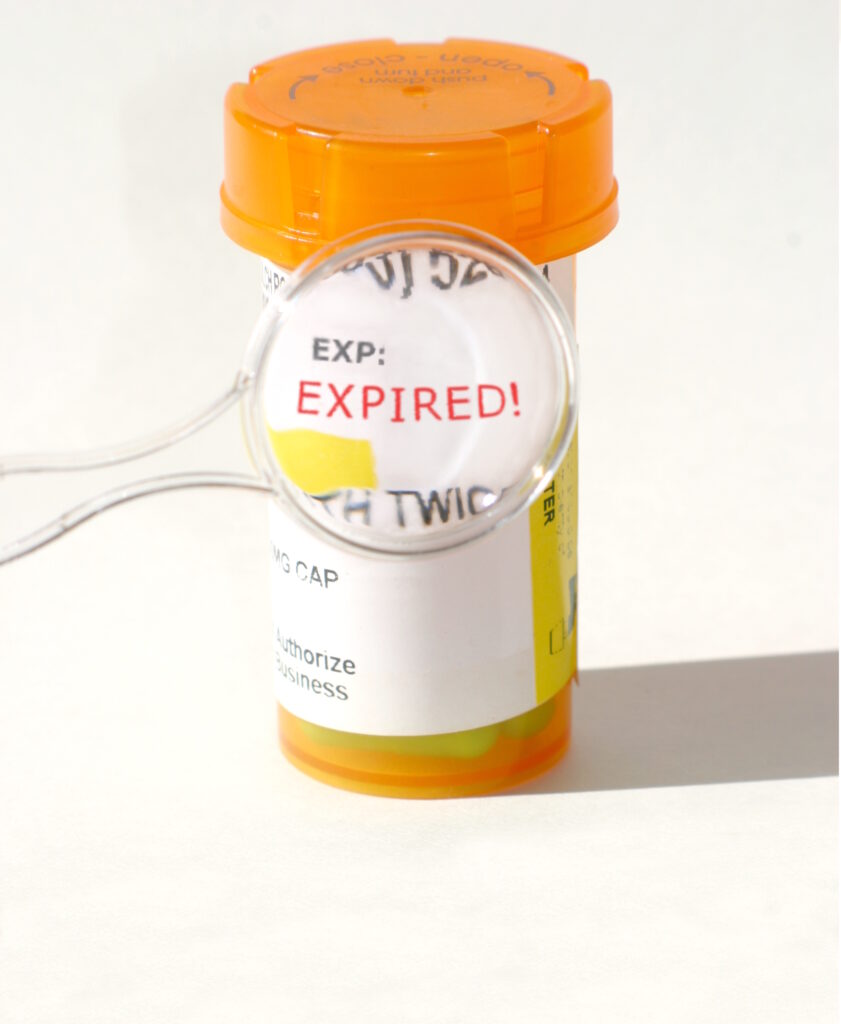 A small magnifying glass zooms in on the word expired on an orange pharmacy pill bottle represents that medications and Adderall expires.