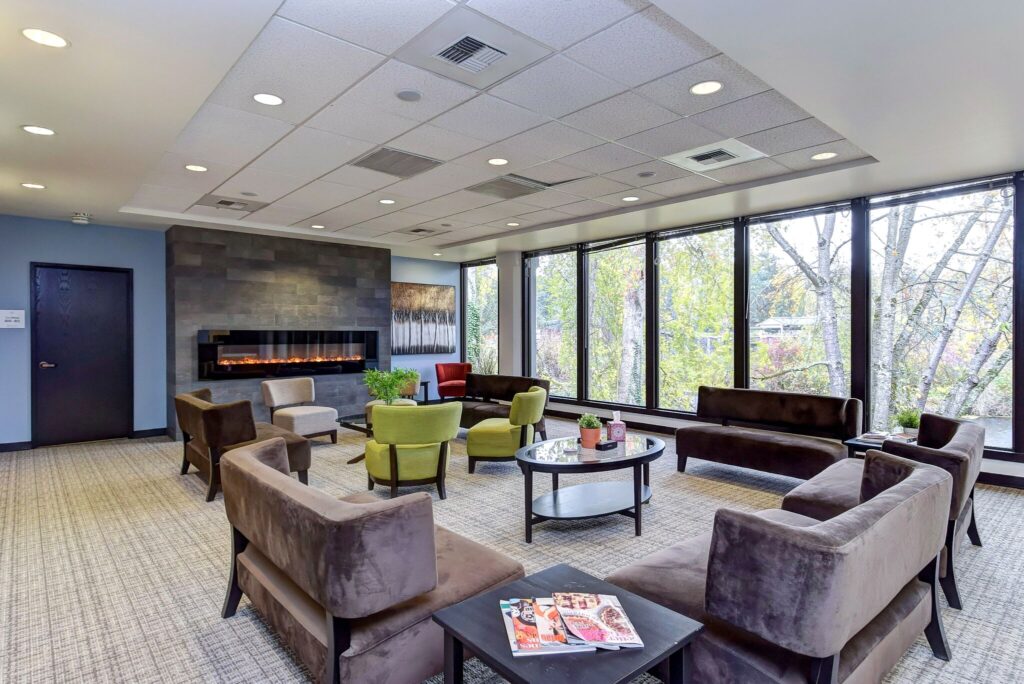 Gray couches and green chairs surrounding fireplace in a Kaiser treatment center.