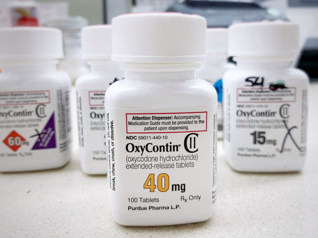 Various bottles of Oxycontin pills on a counter presents the dangers of drinking on oxycodone.