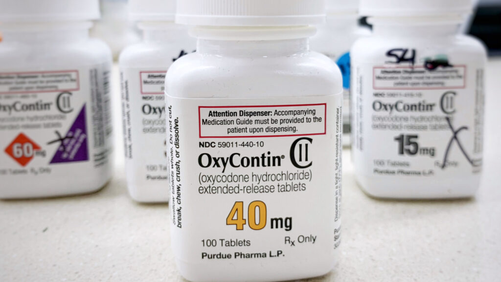 Various bottles of Oxycontin pills on a counter presents the dangers of drinking on oxycodone.