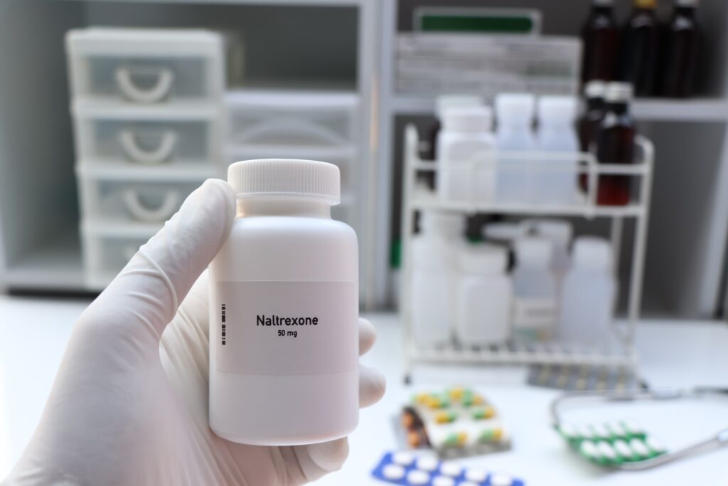 A pharmacists holding a bottle of naltrexone 50 mg represents the effects of naltrexone withdrawal.
