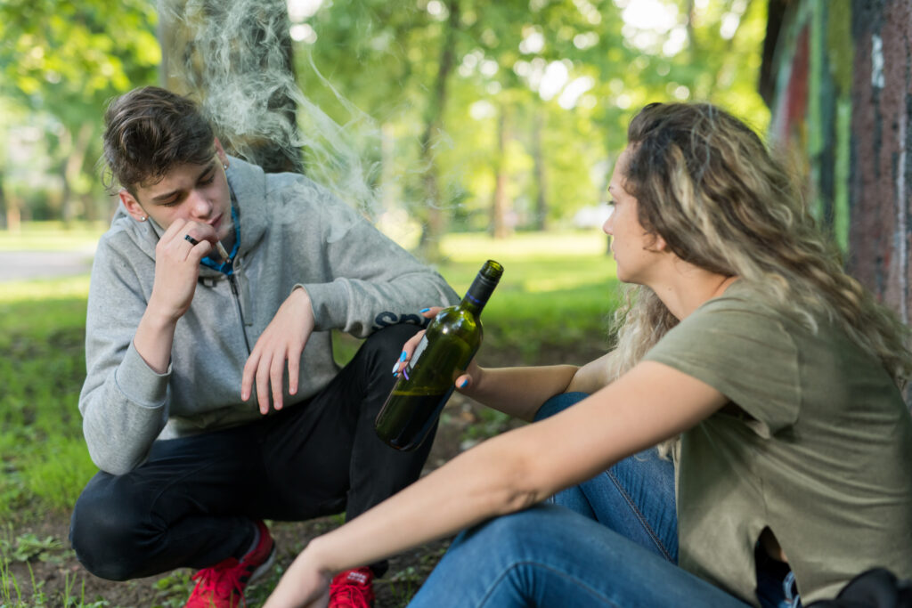 A young man and women smoking marijuana and drinking alcohol getting cross faded.