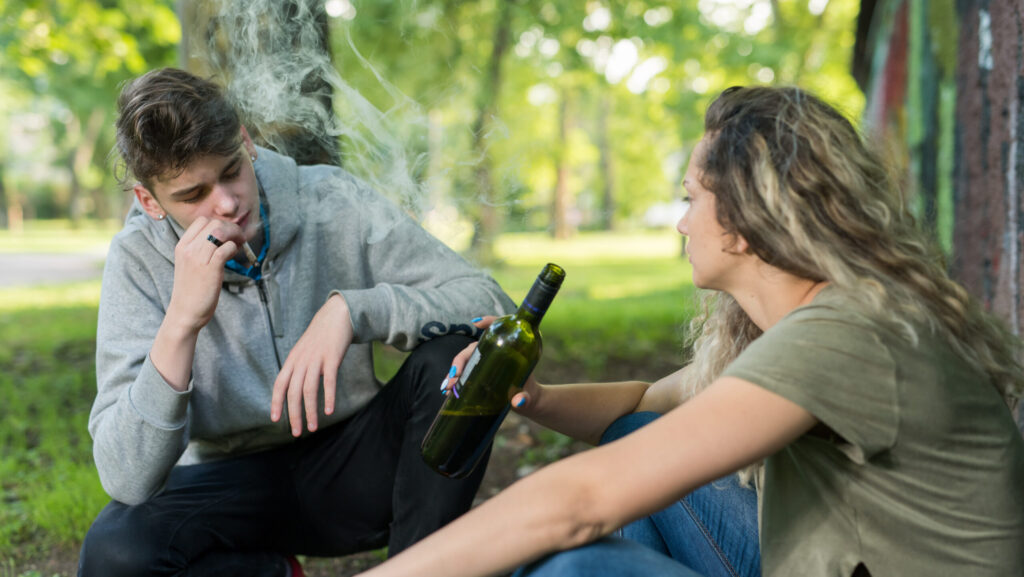 A young man and women smoking marijuana and drinking alcohol getting cross faded.