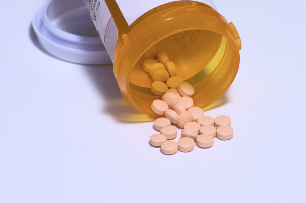 A pharmacy bottle of Flexeril pills is spilled over representing why was Flexeril discontinued.