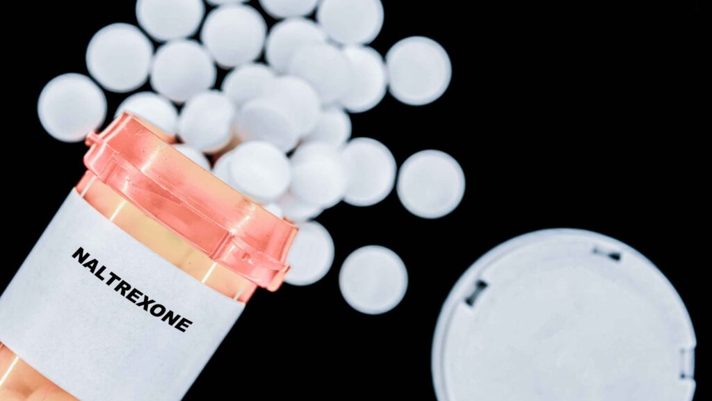 An orange pharmacy bottle of naltrexone is spilled over representing the medication used in the Sinclair Method for Alcohol.