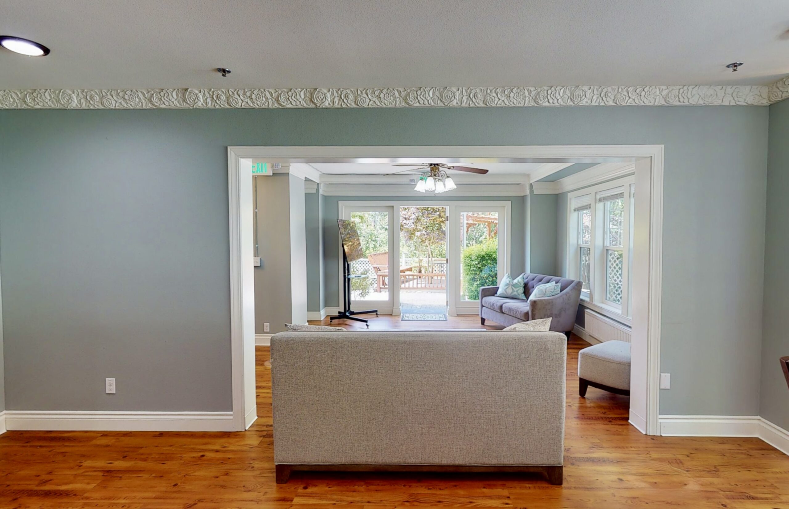 Open view of living room with large doors opening up to a green, sun lit Patio in the Kirkland Washington Medical Detox Home