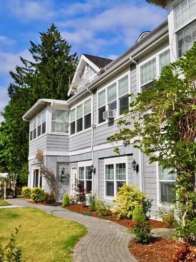 Exterior of historical, blue home used as a medical detox in Kirkland Washington. A Brick sidewalk and flowers border the home