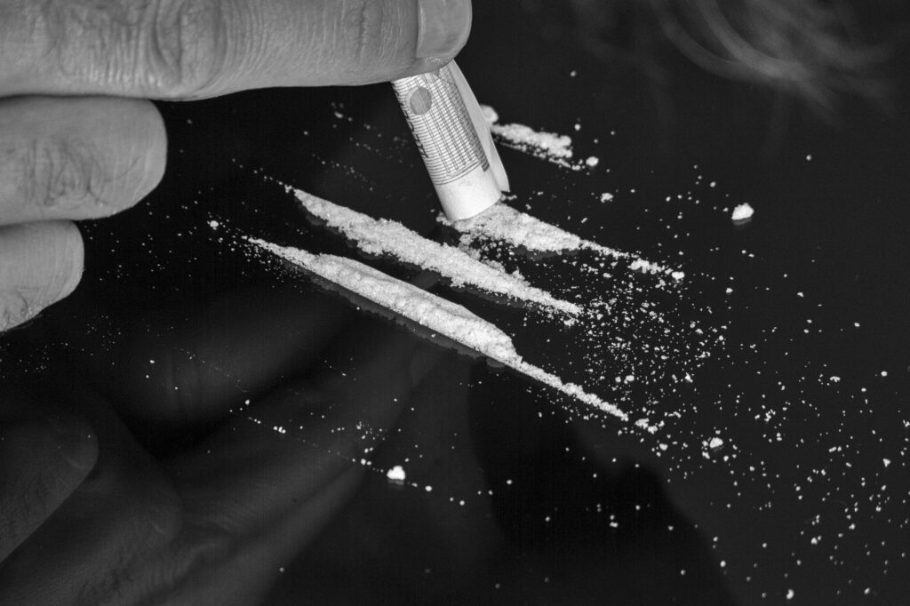 A person snorting lines of heroin with a rolled up bill.