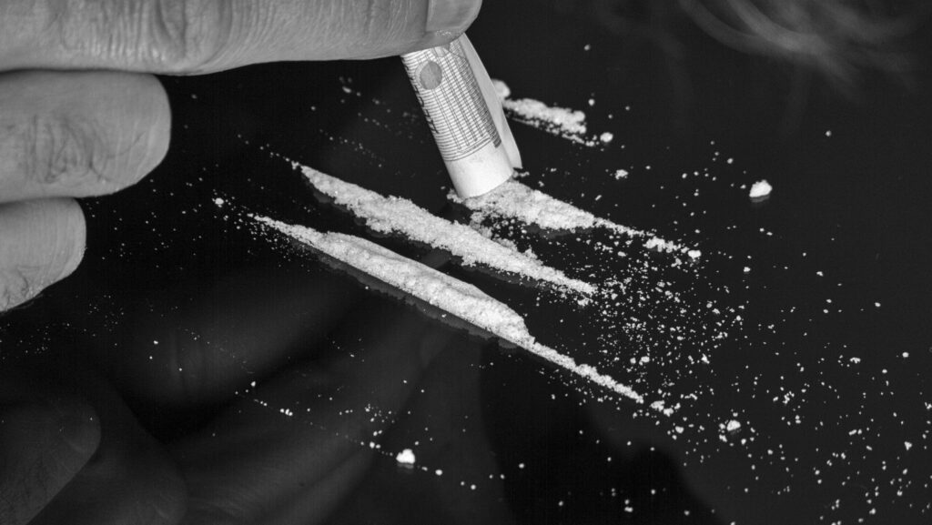 A person snorting lines of heroin with a rolled up bill.