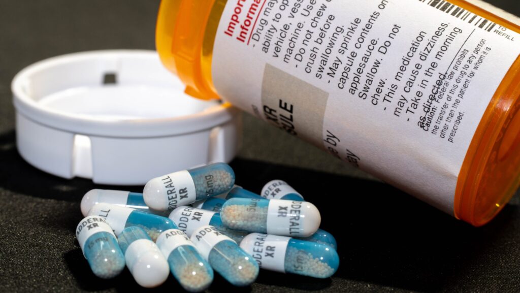 A prescription bottle of a popular amphetamine Adderall XR represents amphetamine use signs.