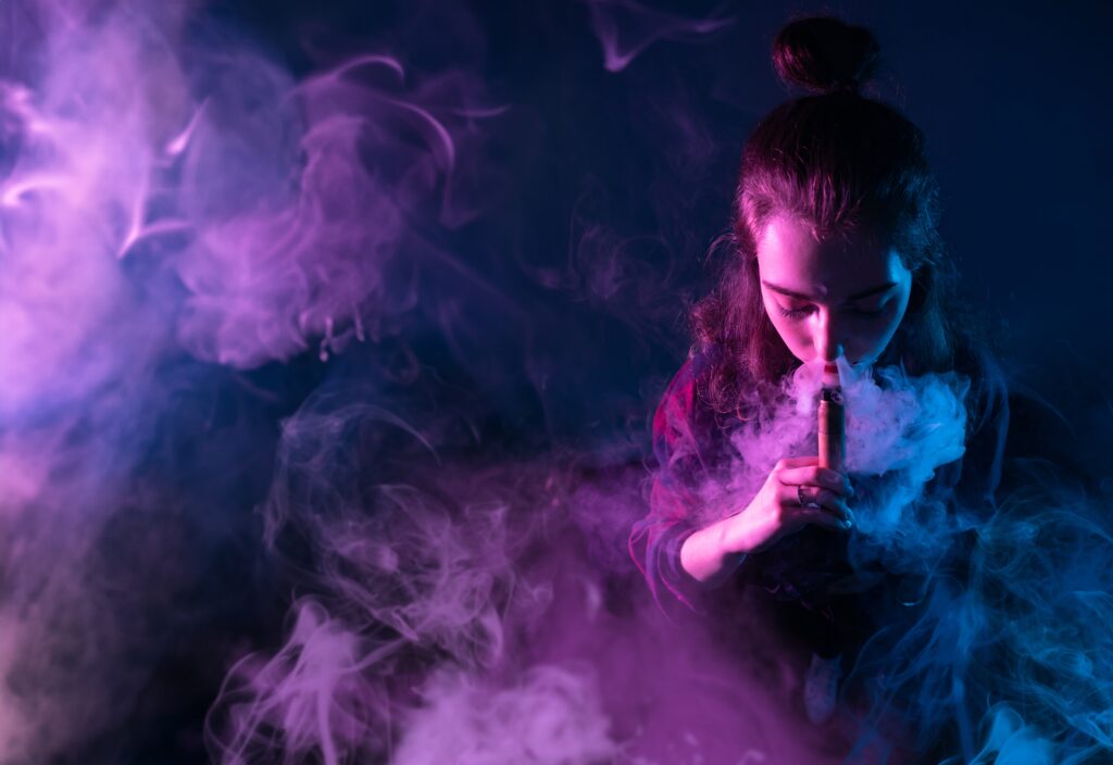 A young woman is inhaling her vape pen loaded with a DMT cart.