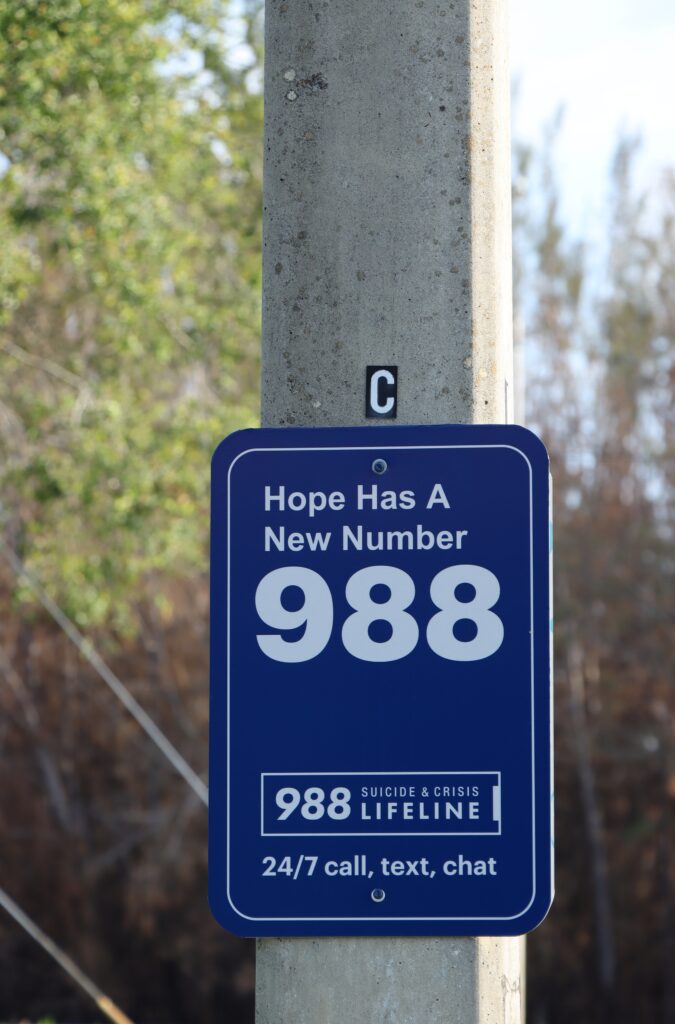 A sign with the 988 Suicide & Crisis Lifeline represents the questions if Trump cut the national mental health hotline.