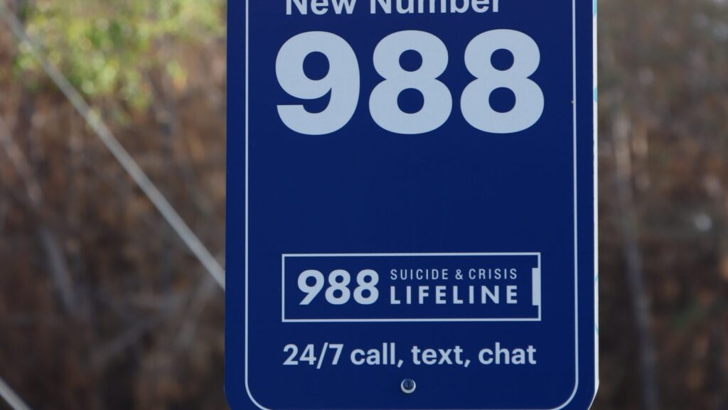 A sign with the 988 Suicide & Crisis Lifeline represents the questions if Trump cut the national mental health hotline.
