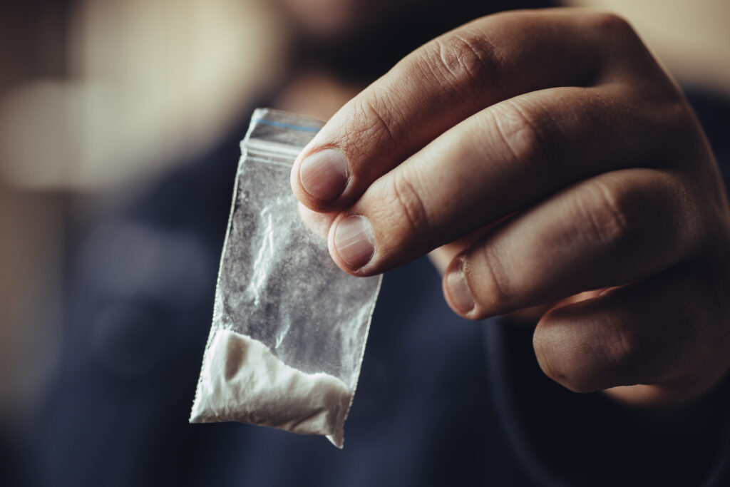 A man holding a small bag of cocaine.